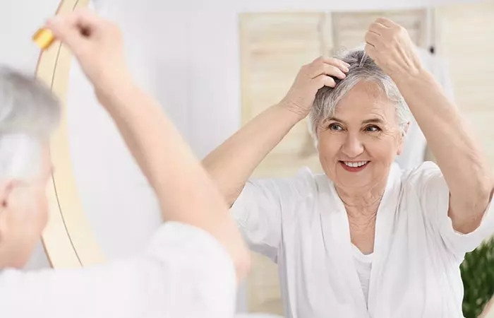 Elderly woman applying hair serum for shiny gray hair