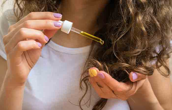 Woman applying hair oil to avoid static hair