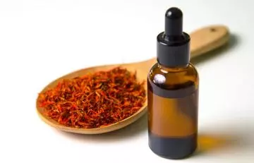 Wooden spoon with dried safflower and a vial of safflower oil for skin care