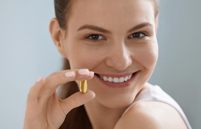 Smiling woman holding vitamin E capsule