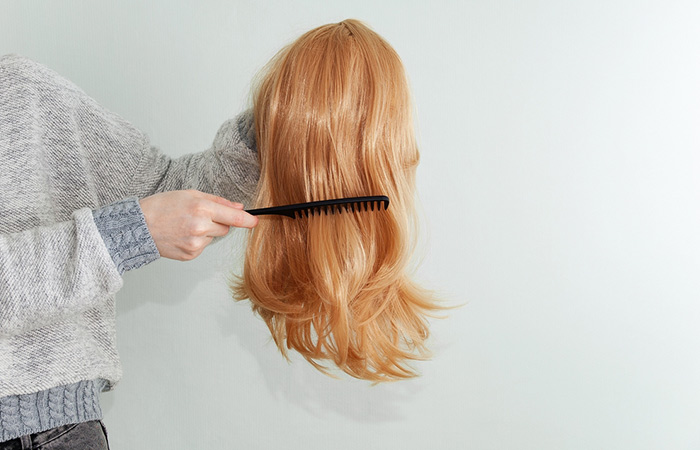 Woman brushing her wig with a wide-toothed comb to remove tangles