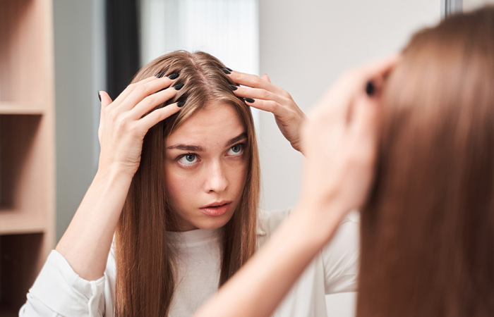Woman checking her hair breakage on the scalp in the mirror