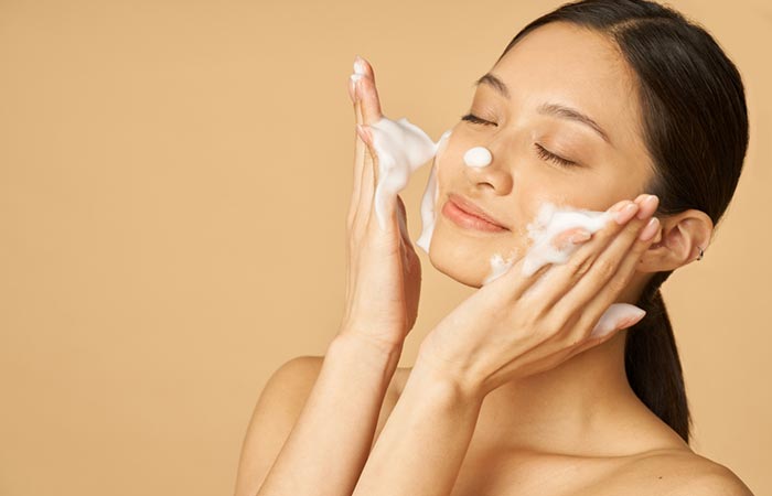 Woman applying face cleanser to begin daytime skin care routine
