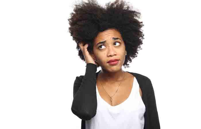 Confused African woman wondering whether to air dry her hair or use a diffuser.