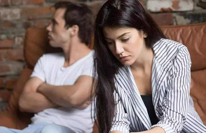 Man looking away as woman looks worried while both are seated.