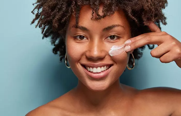 Young woman applying garlic and rosewater mixture to her face for acne