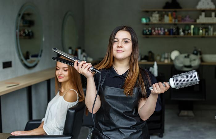 Woman holding hair straightener brush and flat iron