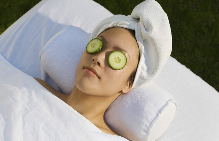 Woman placing cucumber on eyes to treat sunken eyes