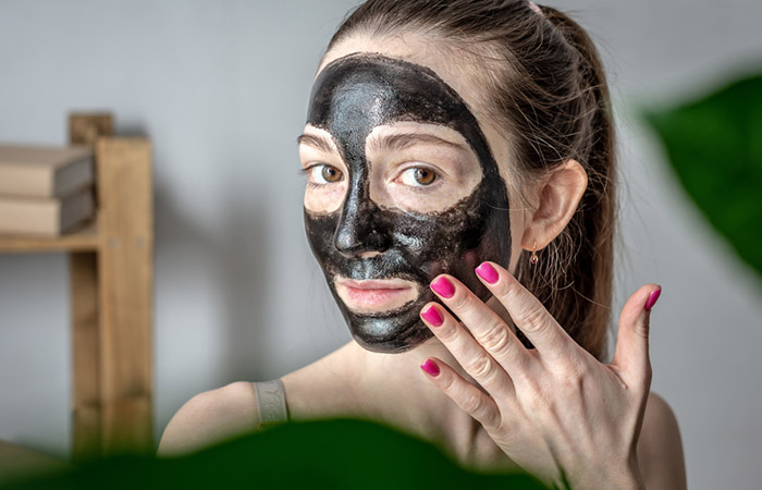 A woman wearing a charcoal mask on her face