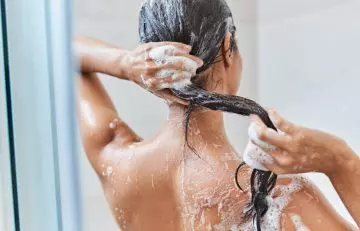 Woman washing her hair regularly to prevent dandruff