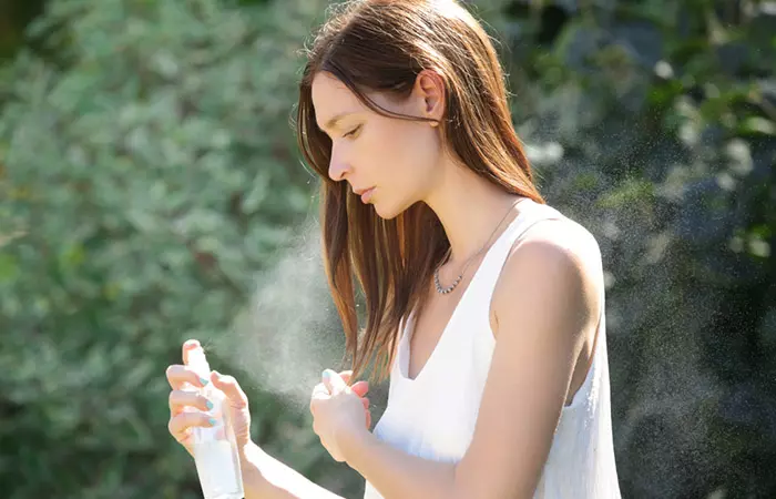 Woman spraying heat protectant to maintain hair gloss