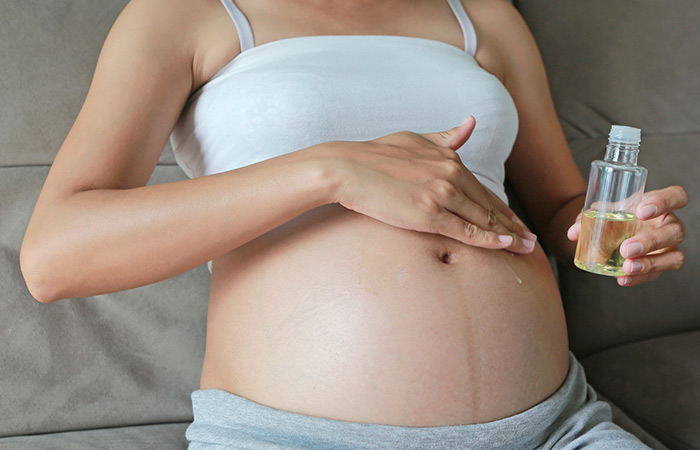 Pregnant woman applying hazelnut oil on her belly
