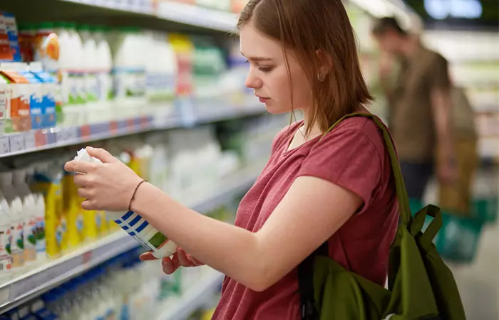 Woman reading ingredients on a clarifying shampoo bottle