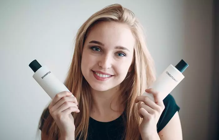 Woman holding a bottle each of shampoo and conditioner in either hand