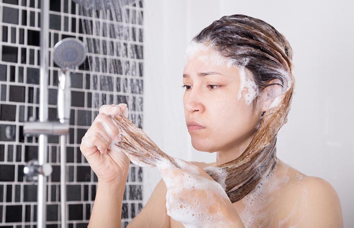 Unhappy woman checking her hair after using expired shampoo