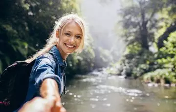 Woman smiling and reaching out to person on the other side of the camera