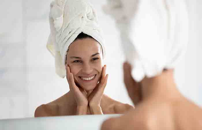Woman looking at her skin in the mirror and feeling happy