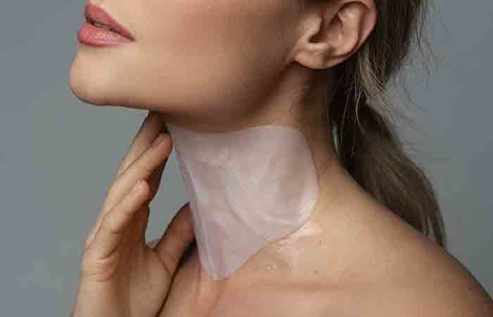 Woman moisturizing her neck with a mask.