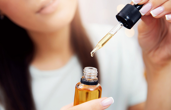 Woman using hazelnut oil with a dropper