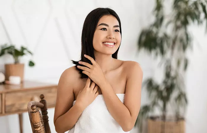 Woman applying heat-protecting serum before curling her fine hair