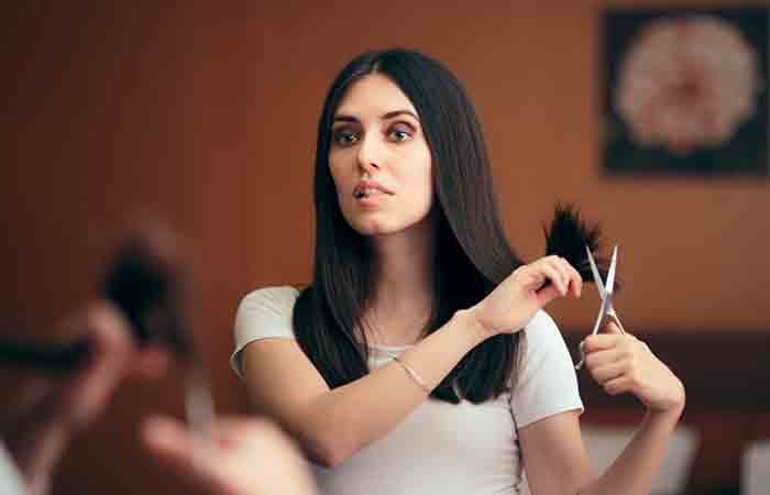 Woman looking in mirror and trimming her hair