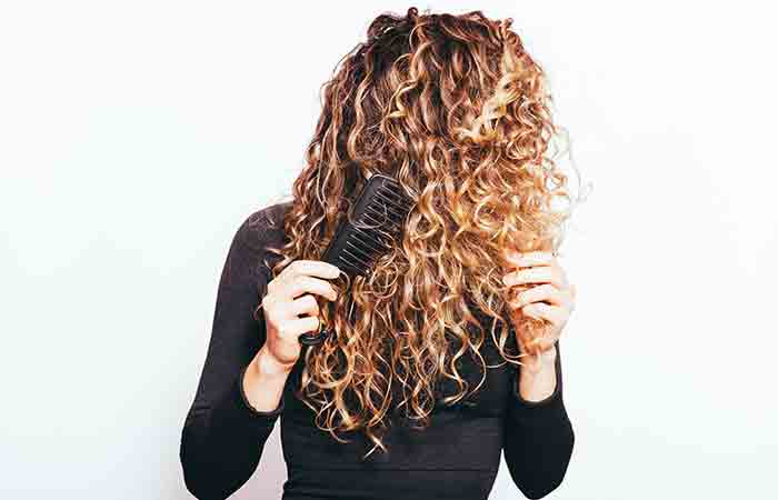 Woman combing her naturally curly hair with a wide-toothed comb
