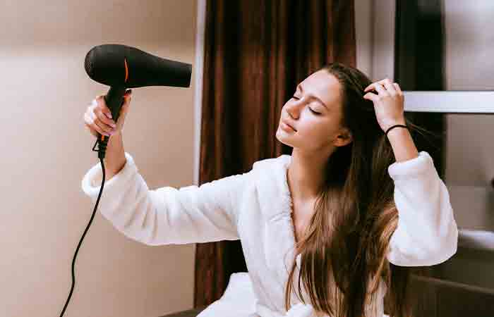 Woman drying hair with hair dryer