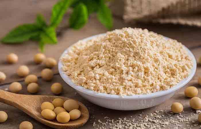 A scoop of soy protein powder amidst soybean as a whey protein alternative