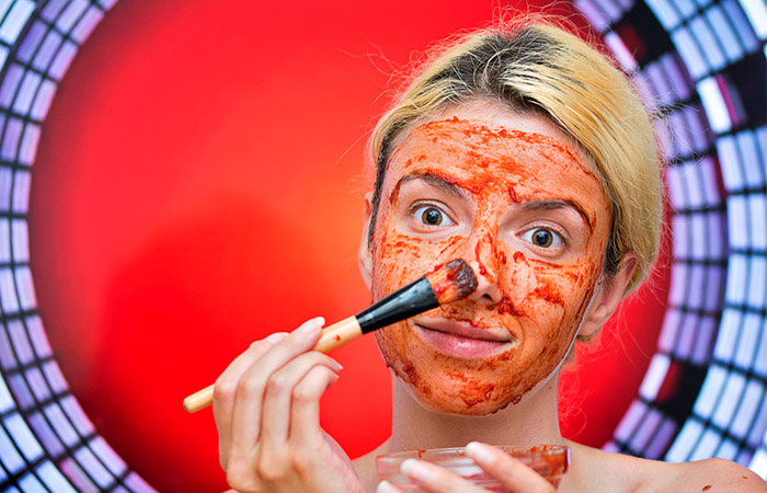 Woman applying tomato paste on face