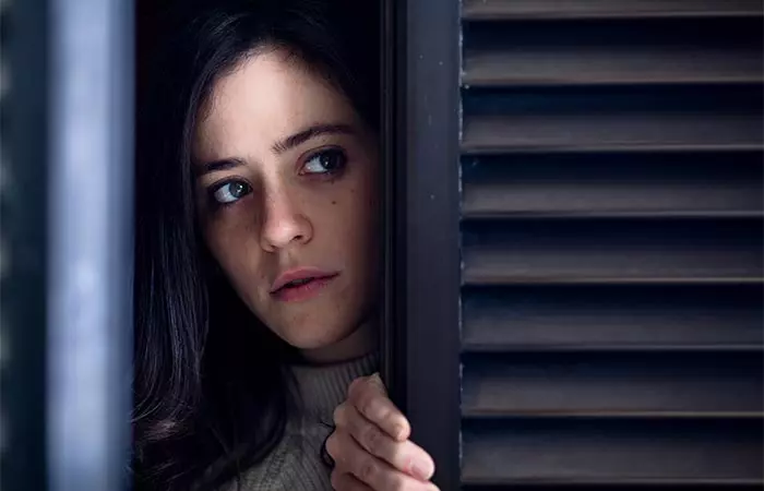 worried-woman-watching-outside-wooden-window