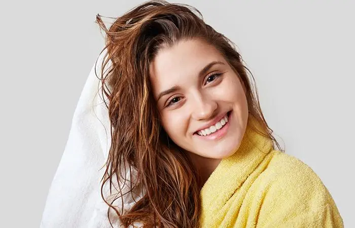 A woman towel drying her hair before applying toner