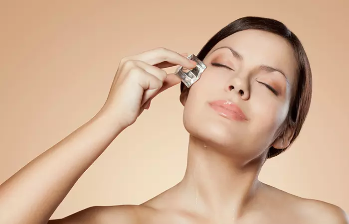 Woman applying ice cube to her face