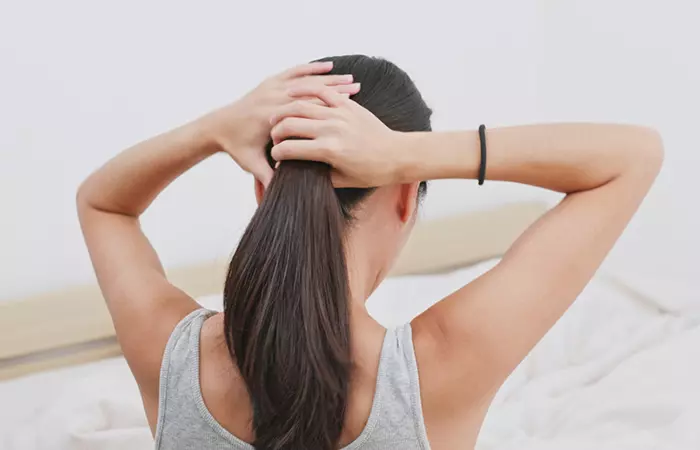 Woman tying her hair loosely to deal with hair loss after surgery