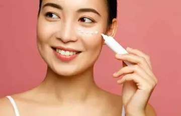 A woman applying eye cream as a part of her morning skin care routine