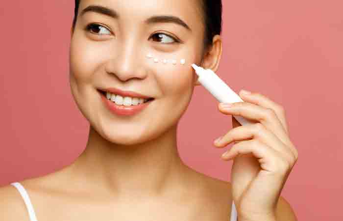 A woman applying eye cream as a part of her morning skin care routine