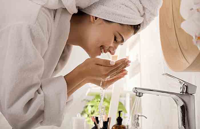 Woman washing her face with cold water