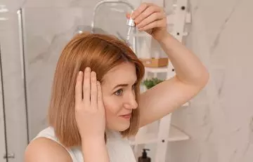 Woman applying arnica oil to the scalp