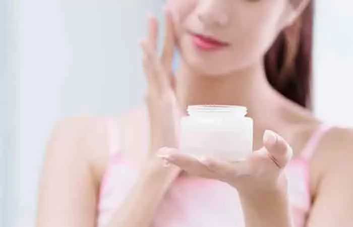 Young woman applying moisturizer as a part of her night skin care routine