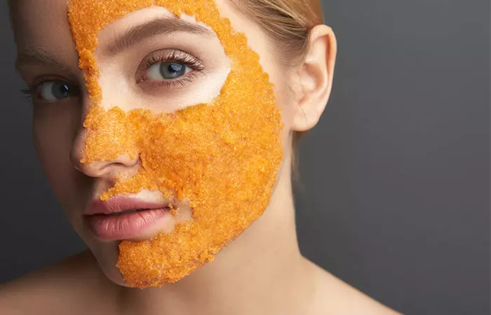 Woman using orange peel face mask as a home remedy to treat having a face darker than the body