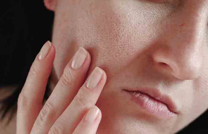 Washing face with cold water may benefit woman who is examining her enlarged skinpores