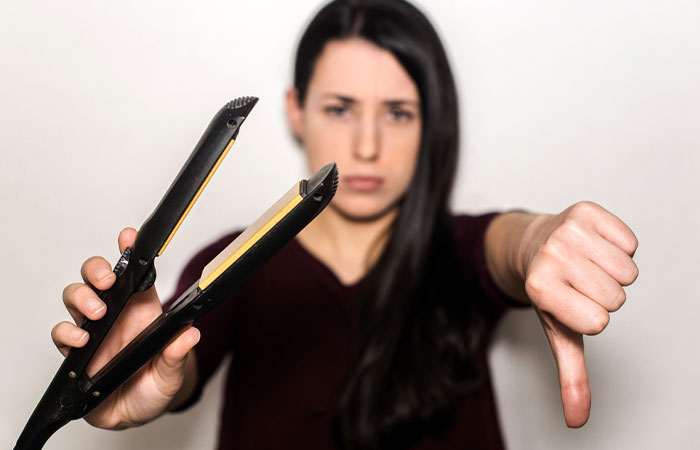 Woman avoiding hair straightener to prevent hair loss due to radiation therapy