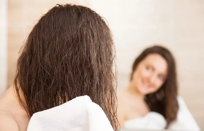 Woman using soft towel to dry hair to avoid hair loss due to radiation therapy