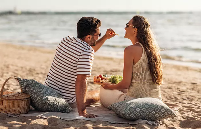 Couple eating fruits on a beach