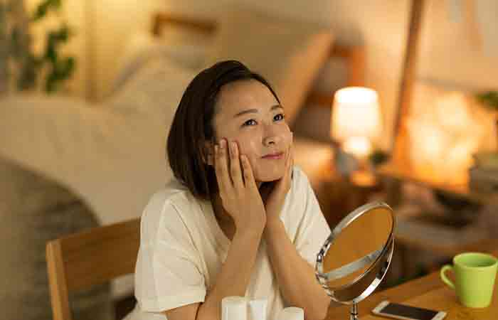 A woman using hyaluronic acid with vitamin C at nighttime to improve her skin