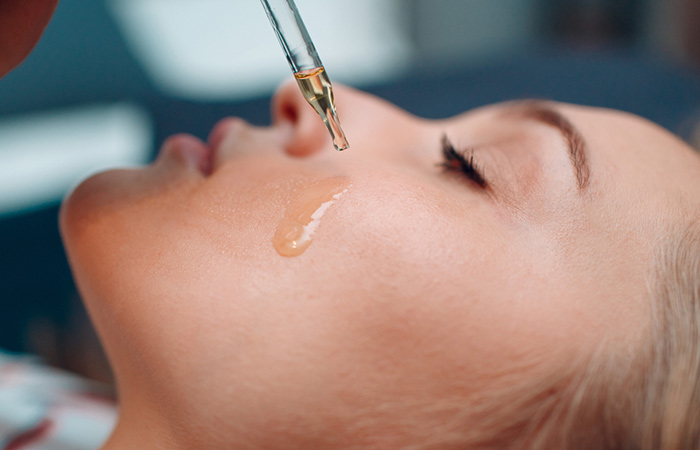Woman applying castor oil on her face using a dropper