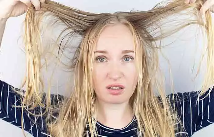 Woman spreads out her dull hair which has a matted texture and does not have a healthy looking shine