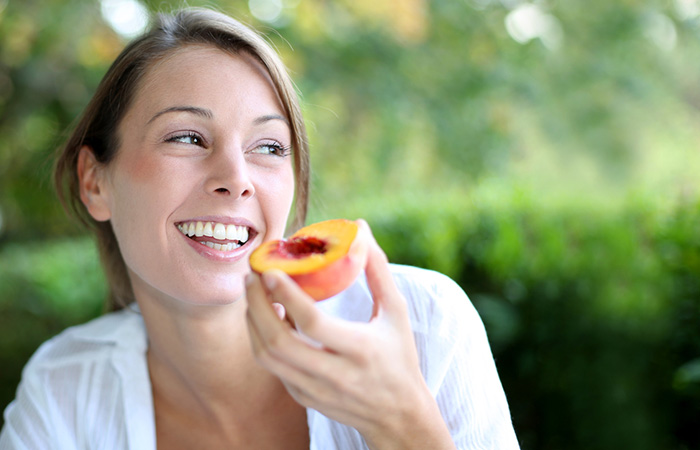 Woman consuming peach for glowing skin