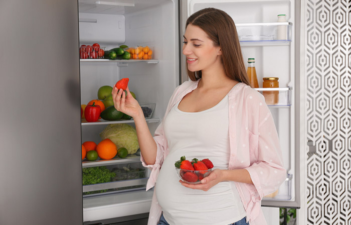 Pregnant woman eating strawberry to flaunt glowing skin