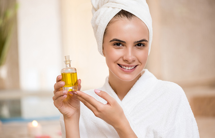 Woman with glowing skin holding a bottle of castor oil