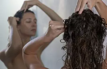 Woman giving herself a scalp massage while shampooing